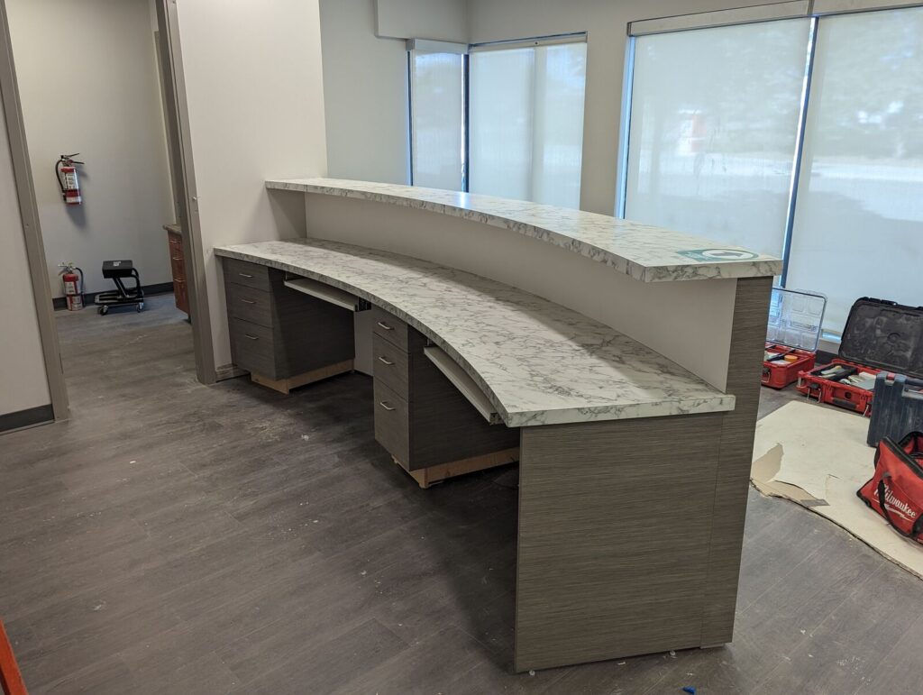 Commercial office fit-out millwork: curved reception desk, office desks and change rooms, Calgary