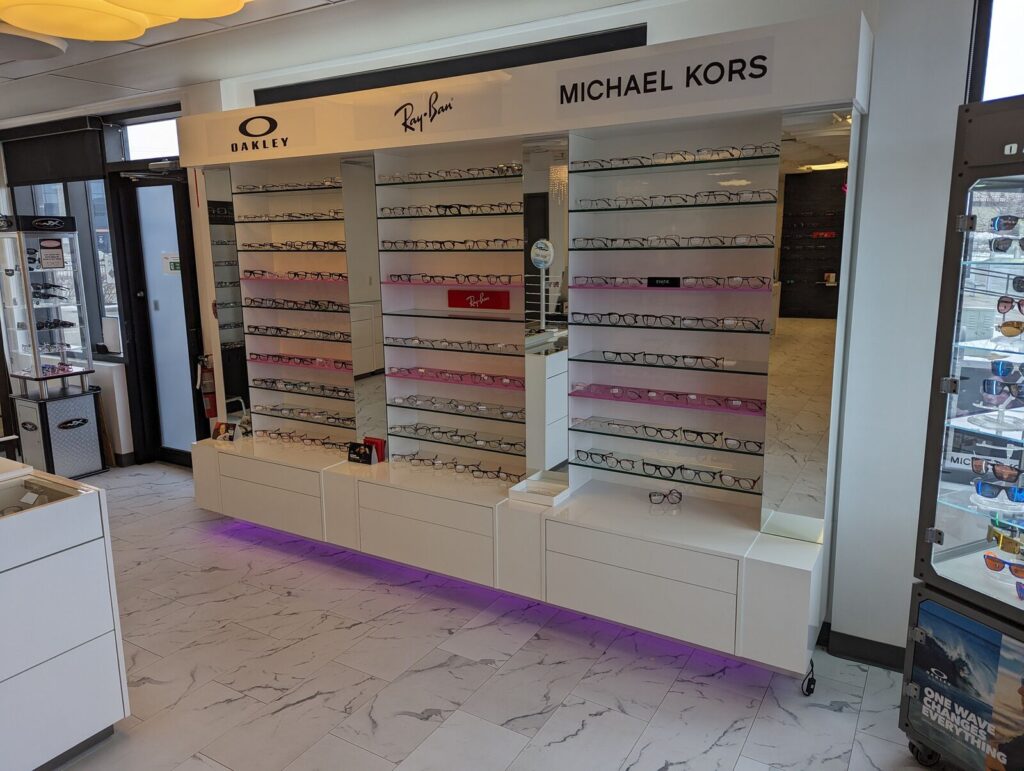 Custom high-gloss white eyewear display wall units with glass shelving, Quarry Park Optik Boutik